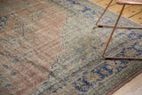 Distressed Oushak rug corner featuring geometric vinery in muted blush and cobalt blue.