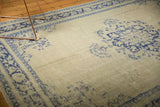Distressed pale celadon Oushak rug showing faded cobalt floral motifs and worn pile.