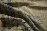 Distressed Oushak carpet close-up: worn celadon green pile with faded cobalt floral motifs.