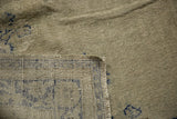Distressed Oushak rug corner: pale celadon pile, blue pattern, and woven reverse side.