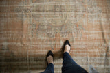 Distressed Oushak rug showing mostly even wear with apricot, beige, and faded blue.