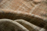 Worn, low pile texture of a distressed vintage Oushak rug in faded apricot and sand.