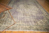Angled detail of vintage distressed Oushak carpet, showing worn pile texture in purple, ivory, blue.