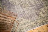 Distressed Oushak carpet with purple, antique ivory, slate blue, faint foundation showing, fringe.