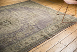 Vintage distressed Oushak rug with secured side, showing faded purple and ivory tones.