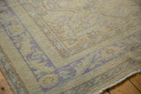 Distressed pile texture with faded blue scrolling motifs on a vintage Oushak rug border.