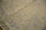 Close-up of distressed vintage Oushak rug's muted beige pile and faded scrolling leaf border.
