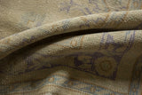 Distressed vintage Oushak rug pile with faded beige, soft purple, and pale brown scrolling patterns.