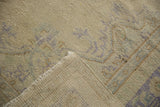 Distressed beige Oushak rug pile with faint blue pattern and visible woven foundation.