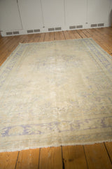 Distressed Oushak rug detail, showing faded Rococo patterns, worn texture, and pale tones.