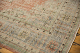 Distressed vintage Oushak rug corner with faded denim blue border and terra cotta motifs.