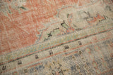 Distressed pile of vintage Oushak rug, showing worn terra cotta, faded blue, and green patterns.