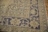 Distressed Oushak rug corner with faded cobalt blue floral border on antique ivory.