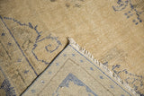 Distressed Oushak rug with hand-knotted foundation revealed, showing ivory fringe.