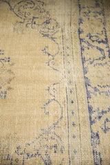 Distressed vintage Oushak carpet pile featuring faded pale ivory and cobalt blue patterns.