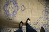 Distressed vintage Oushak rug, showing faded ivory field and cobalt blue palmette motifs.