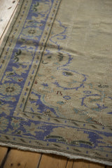 Distressed vintage Oushak carpet corner, faded cobalt leaf and palmette border, visible wear.