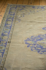 Faded cobalt blue palmette border, pale ivory field, and even wear on distressed Oushak rug.