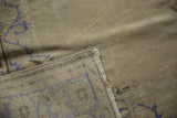Worn pale ivory pile and faded blue pattern detail on distressed Oushak carpet.