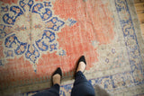 Distressed vintage Oushak carpet, showing worn texture, faded blush red and cobalt blue.