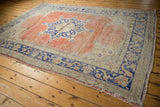 Curvilinear cobalt blue border design with distressed finish and worn beige fringe.