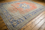 Distressed vintage Oushak carpet corner, showing worn texture, secured edge, and blue border design.