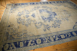 Heavy abrashes and cobalt blue floral border on a distressed ivory Oushak rug.