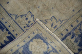 Distressed Oushak rug corner showing textural pile, cobalt blue patterns, and woven foundation.
