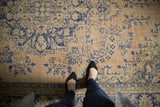 Distressed vintage Oushak rug's pale rose apricot field with faded cobalt blue vinery.