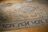 Distressed hand-knotted Oushak corner featuring faded apricot, cobalt blue floral and geometric patterns.