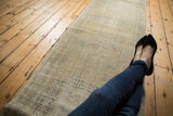 Distressed vintage Oushak runner with faded ivory, blue, green tones and geometric patterns.