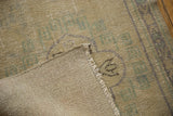 Distressed vintage Oushak rug showing pile texture, visible foundation, and fringe.