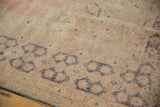 Distressed Oushak rug pile with foundation showing, featuring pale blush and dusty navy motifs.