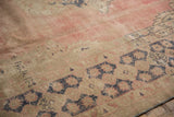 Visible foundation and even wear on distressed Oushak rug in faded blush and blue.