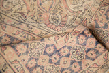Distressed vintage Oushak rug, blush and navy Rococo motifs, showing textural wear.