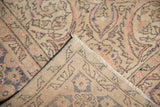 Distressed Oushak carpet corner, showing worn pile, blush, navy curvilinear motifs, and foundation.