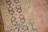Distressed vintage Oushak rug pile texture with pale blush and dusty navy patterns.