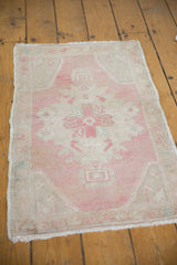 Distressed Oushak rug corner, revealing pale pink Rococo contour and ivory spandrel.