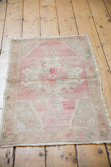 Decorative distressed Oushak rug corner detail with soft pale pink, beige pile, and secured side.