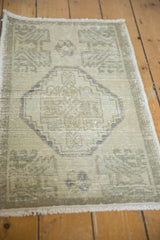 Distressed Oushak rug's stepped center medallion in antique ivory and oxidized silver tones.