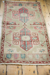 Scrolling rams horn and pomegranate motifs on a distressed Oushak rug in dusty red and aqua.