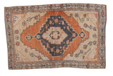 Distressed vintage Oushak rug with stepped medallion, floral designs in rust, navy, and ivory.