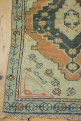 Hand-knotted distressed Oushak rug corner with faded copper, navy, and ivory floral border.