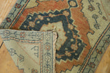 Folded vintage Oushak rug revealing hand-knotted foundation and distressed copper, ivory, navy pile.