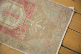 Distressed vintage Oushak rug corner with pale pink, beige, and powder blue scrolling tendrils.