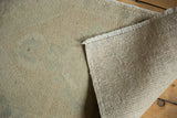Distressed Oushak rug showing worn beige pile, secured fringe, and hand-knotted foundation.