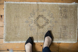 Vintage distressed Oushak rug mat with subtle medallion on worn ivory and pale gray field.