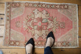Distressed Oushak rug corner with pale pink abrashes, ivory spandrel, and bronze border.