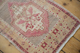 Stepped geometric medallion and pale cochineal red floral design on distressed Oushak rug.