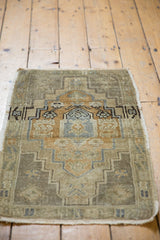 Distressed vintage Oushak rug mat, visible abrashes, stepped medallion, gold, ivory, charcoal.